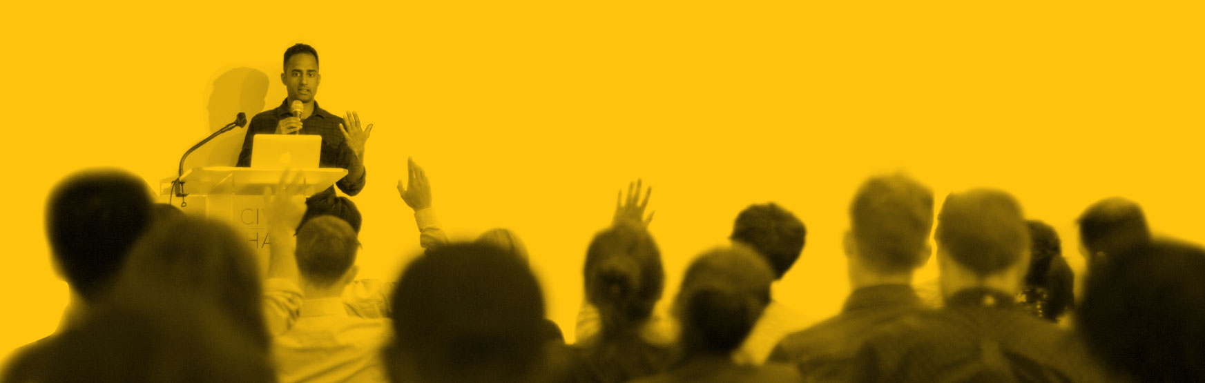 A man speaks in front of a crowd at a Civic Hall event.